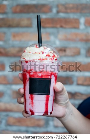 A girl holds a strawberry smoothie. Female hand holding milk shake 