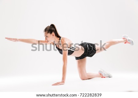 Full length portrait of a healthy fit sportswoman holding balance during exercise isolated over white background