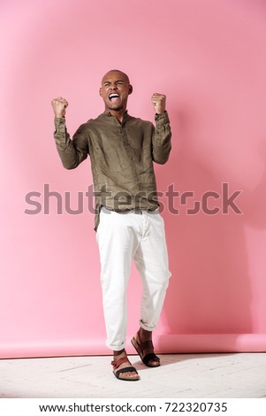 Full length image of happy screaming african man over pink background