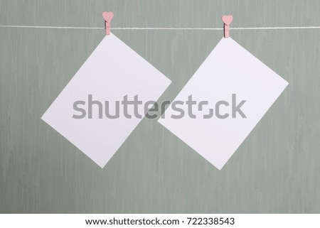 Photographic prints hang after developing on a cord and dry. There is a place to insert your content. Attached to the cord with clothes pegs in different positions. On a gray-green background.