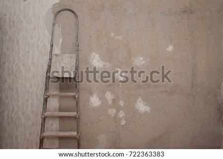 Old concrete wall with torn Wallpaper. a ladder against the wall,