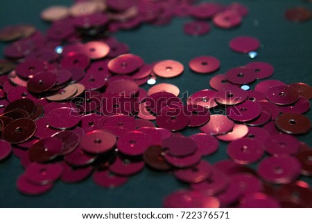 Abstract red glitter background. Shiny sequins on dark table.