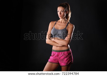 Fitness trainer posing on black background.
