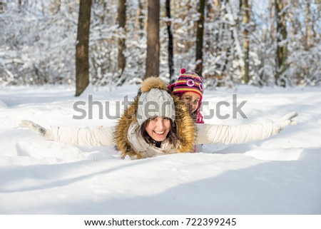Happy daughter and mother in the snow forest