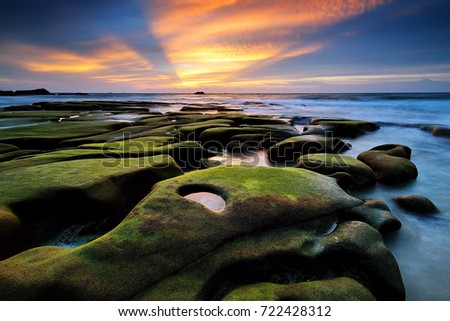 Sunset view with rocks covered by green moss at Tindakon Dazang Beach, Kudat Sabah. Famous place and most photographers to take a pictures.