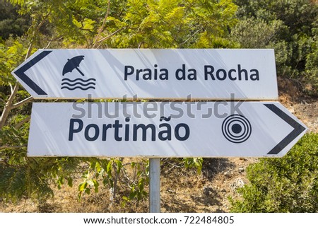 Direction signs for Praia da Rocha, known as Rocha Beach in English, and the town of Portimao in the Algarve region of Portugal.