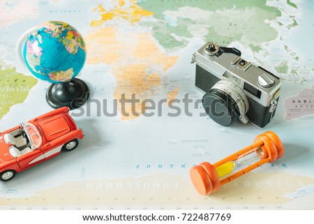 top view. retro camera, world, toy car, sand clock and passport placed on top of color world map are background. this image for international, travel, equipment, country, photography concept