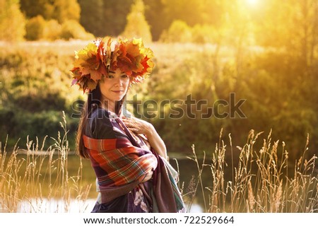 Beautiful woman with wreath of maple leaves in autumn forest on a sunny day. Great season picture with fall mood. Nature september and october composition.