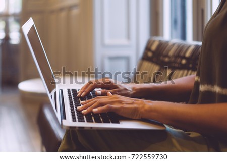 Close up shot of a lady's hands typing e-mail on a keyboard of a portable computer. Young business woman is working on a laptop during coffee break. Student girl is chatting with friends.