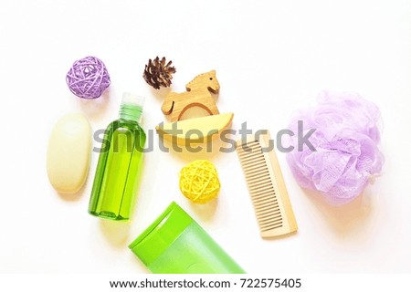 Soap, green massage essential oil, toy wooden horse, shampoo, hair brush and purple sponge puff on a white background. Shower supplies. Natural organic bath products