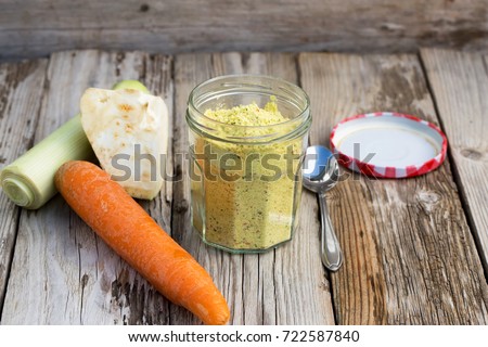 Organic vegetable stock in a glass on wooden table. With celeriac, carrot and onion. Natural light, selective focus. 
