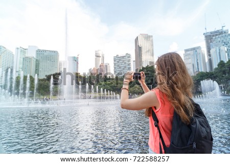 Woman takes pictures in the main square of Kuala Lumpur near the singing fountain