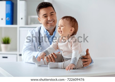 medicine, healtcare, pediatry and people concept - happy doctor or pediatrician holding baby on medical exam at clinic Royalty-Free Stock Photo #722609476