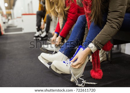 people, winter and leisure concept - close up of woman putting on ice skates