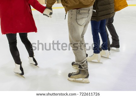 people, winter and leisure concept - close up of friends on skating rink