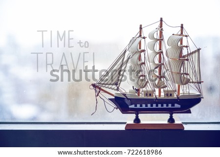 The model of a sailing ship stands on a misted window. The concept of travel. Dreams of a vacation. It's time to go to the sea With the inscription time for travel