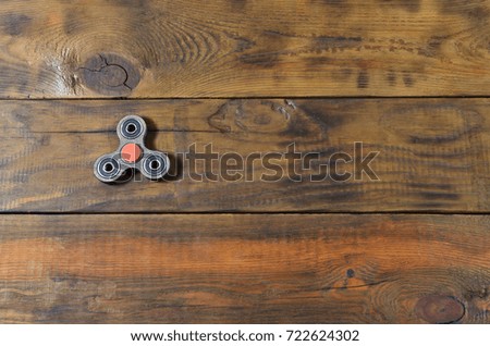 A rare handmade wooden fidget spinner lies on a brown wooden background surface. Trendy stress relieving toy
