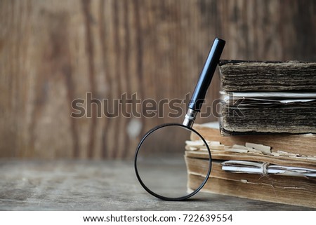 Old books on a wooden table and glass magnifier
