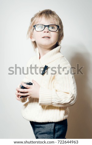 Portrait of young child holding photography camera on light background. Close up picture of equipment study and play activity