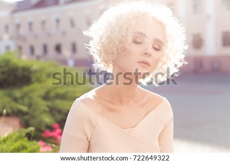 beautiful young curly blond girl outdoors in the sun at sunset on a bright day