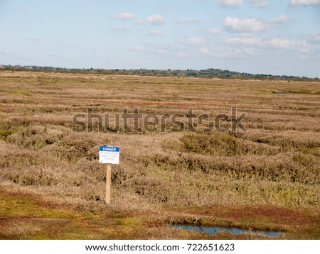 marshland scene outside with danger sign up front; essex; england; UK