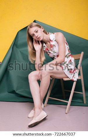 young blonde girl with a slender figure posing in a photo Studio. light summer dress. long hair and problematic skin: acne. emotional portrait