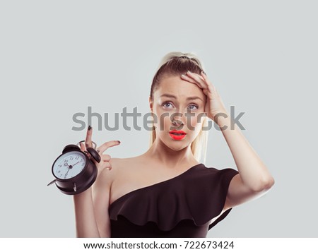 Oh, I forgot to change the time I got a date and it is already late. Young woman holding alarm clock stressed running late isolated white light grey background wall