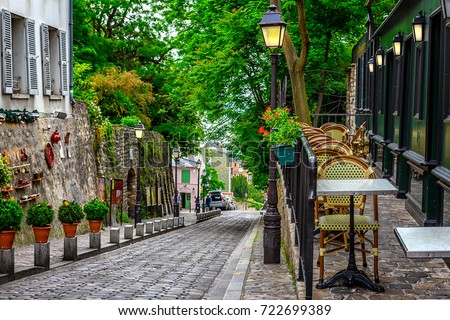 Street with tables of cafe in quarter Montmartre in Paris, France. Cozy cityscape of Paris. Architecture and landmarks of Paris.  Royalty-Free Stock Photo #722699389