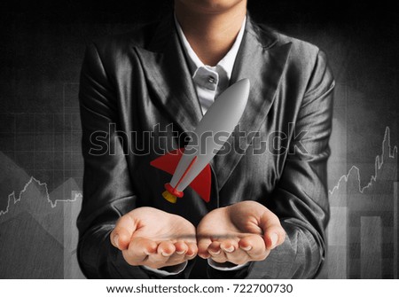 Cropped image of businessman in suit presenting missile in his hands with dark wall on background. 3D rendering.