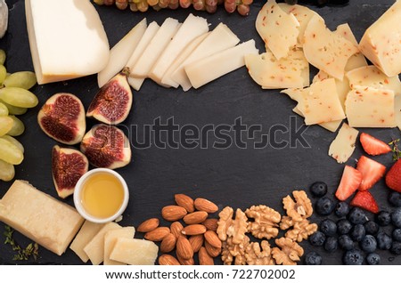 Tasting cheese dish with fruits, berries on old black cheeseboard. Food for wine and romantic, cheese delicatessen. Menu design horizontal. Top view. space for text