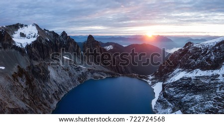 Aerial panorama of a beautiful rugged mountain landscape with a cold glacier lake during sunrise. Picture taken far remote East of Vancouver and Seattle in Washington, USA. 
