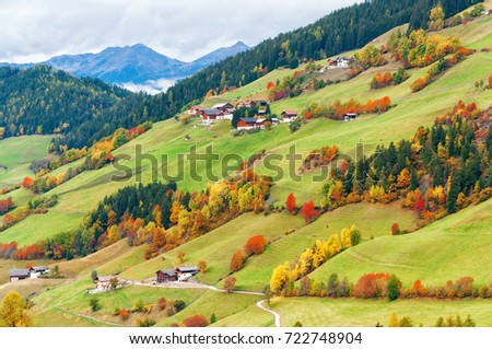 Amazing autumn scenery of mountain hill with buildings and colorful trees and mountains on background. Location place: Santa Maddalena, South Tyrol, Dolomite Alps, Italy. Beautiful nature background. Royalty-Free Stock Photo #722748904