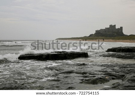 Wave crashes over rocks at Bamburgh beach
