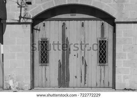 Flaked gate in historic part of Valletta. Entrance to an abandoned house on the island of Malta. Black and white picture
