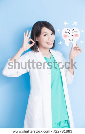 woman dentist take tooth board and show ok to you on the blue background