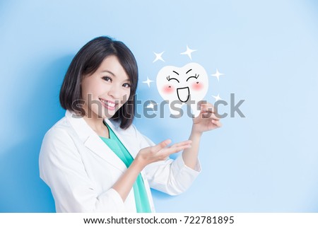 woman dentist take tooth board and show something on the blue background