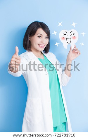 woman dentist take tooth board and thumb up on the blue background