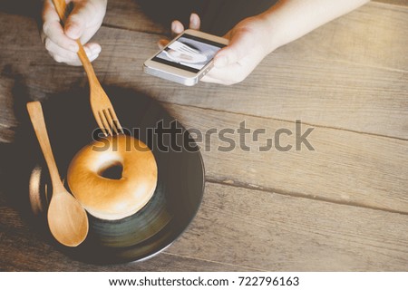 Woman's hands relaxing with donut at donut shop Women, smartphone Take pictures before eating