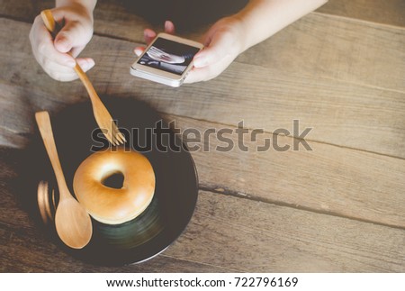 Woman's hands relaxing with donut at donut shop Women, smartphone Take pictures before eating