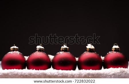 Old used red Christmas baubles with snow on a dark background