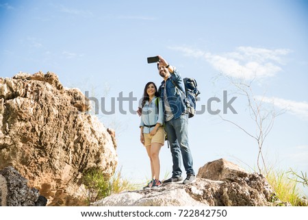 Man taking a picture of him and his girlfriend at the top of a mountain 
