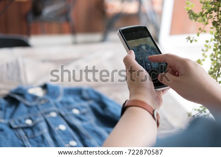 young start up small business owner holding mobile phone and take photo of her product. freelance woman use smart phone to take picture and sell cloth on website. Online selling, e-commerce concept