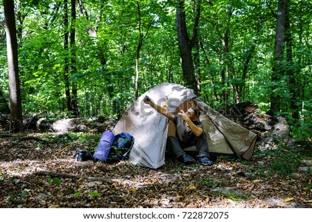 A young tourist is resting in the forest in a tent.