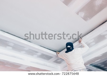 hand of worker using gypsum plaster ceiling joints at construction site Royalty-Free Stock Photo #722875648