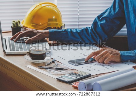 interior designer hand working with new modern computer laptop and smartphone with sample material board on wooden desk as concept