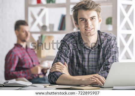 Portrait of handsome european boy using laptop at workplace. Technology and communication concept