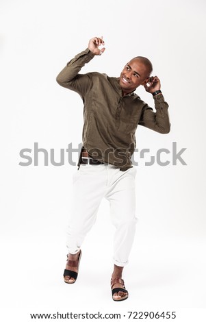 Full length image of happy african man dancing and looking away over white background