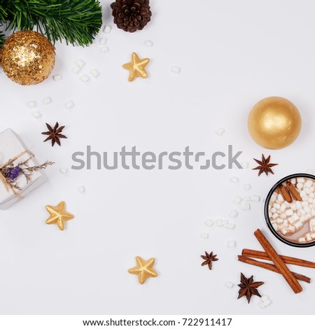 Christmas frame made of pine branches, pine cone, cup of hot chocolate drink with marshmallows, cinnamon sticks, anise star, gift box and golden ornaments on white background. flat lay, top view.