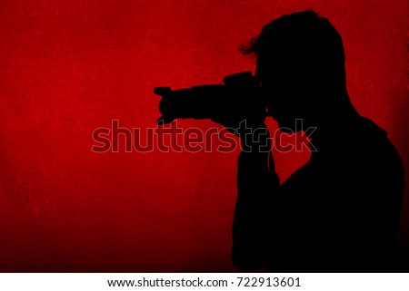 Silhouette of professional male photographer taking pictures with modern camera