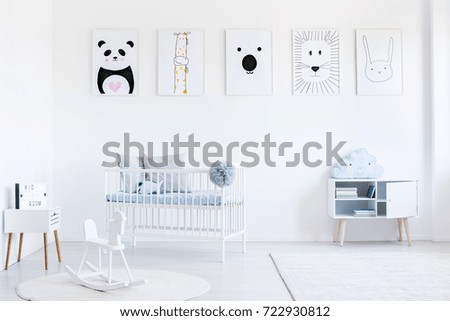 Blue pillow on white cupboard in bright child's bedroom with rocking horse and posters gallery on wall